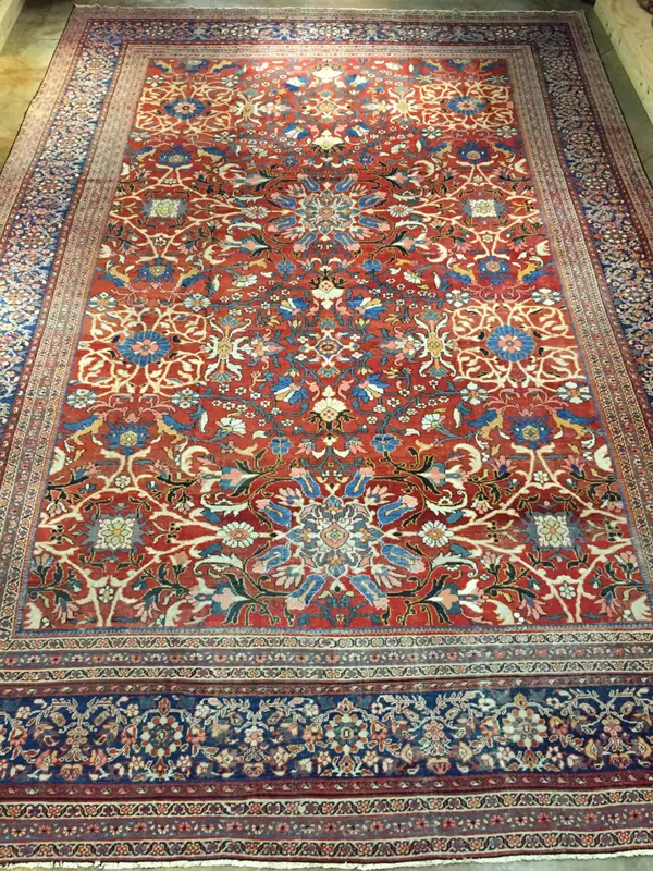 Intricate Persian rug with a rich red base and ornate blue-and-cream floral patterns