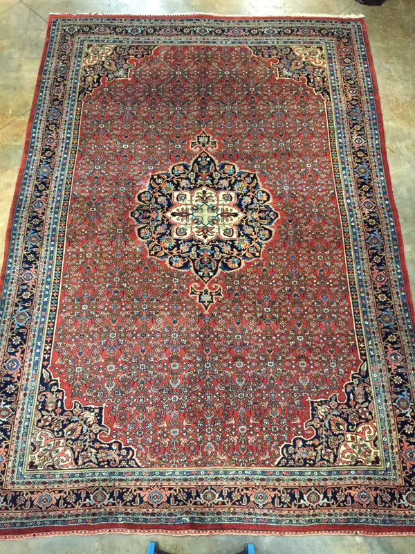 Intricate Persian rug with a red base, central floral medallion, and elaborate borders in blue and beige